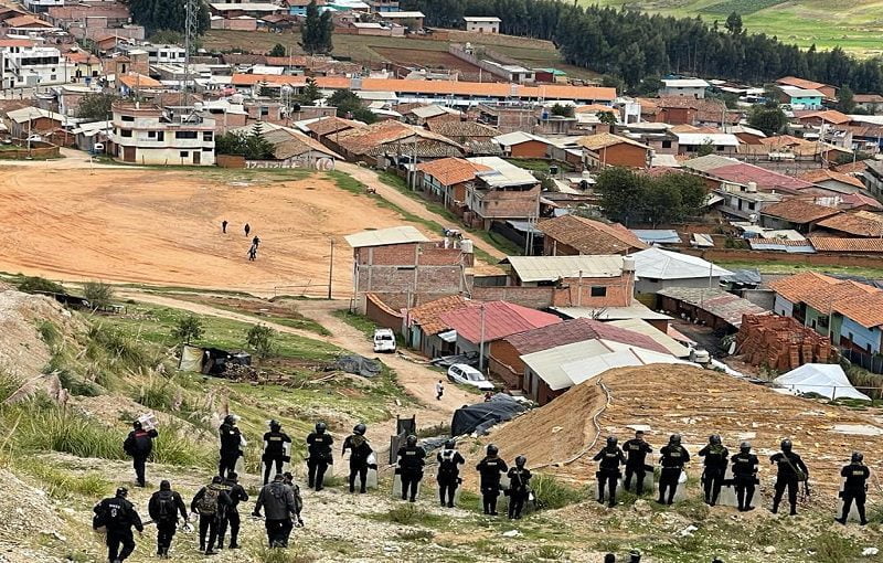 Policías forman una linea sobre un cerro en Pataz. Se observan los techos de las casas en su mayoría de color rojo.