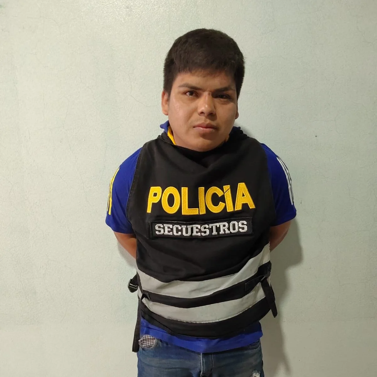 Policía capturado tiene los brazos en la espalda