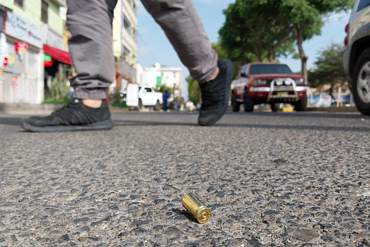 Casquillo de bala en la pista y al fondo un auto