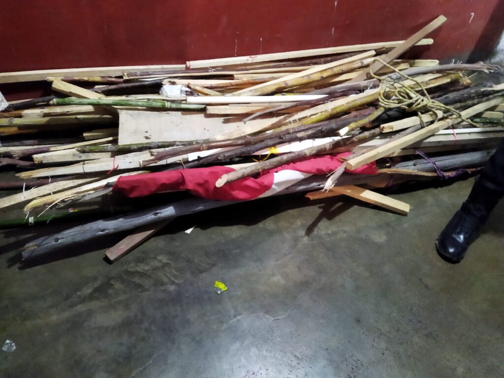 Palos de madera y entre ellos una bandera sobre el piso que fue incautada en las protestas en Perú