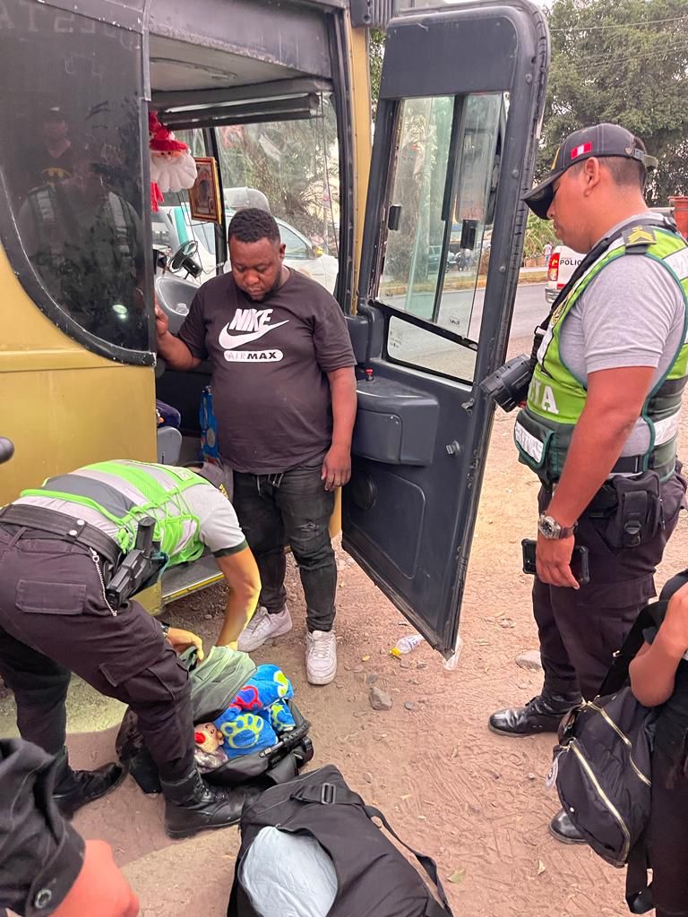 Policía revisa equipaje que se encuentra en el suelo y al lado observa un pasajero