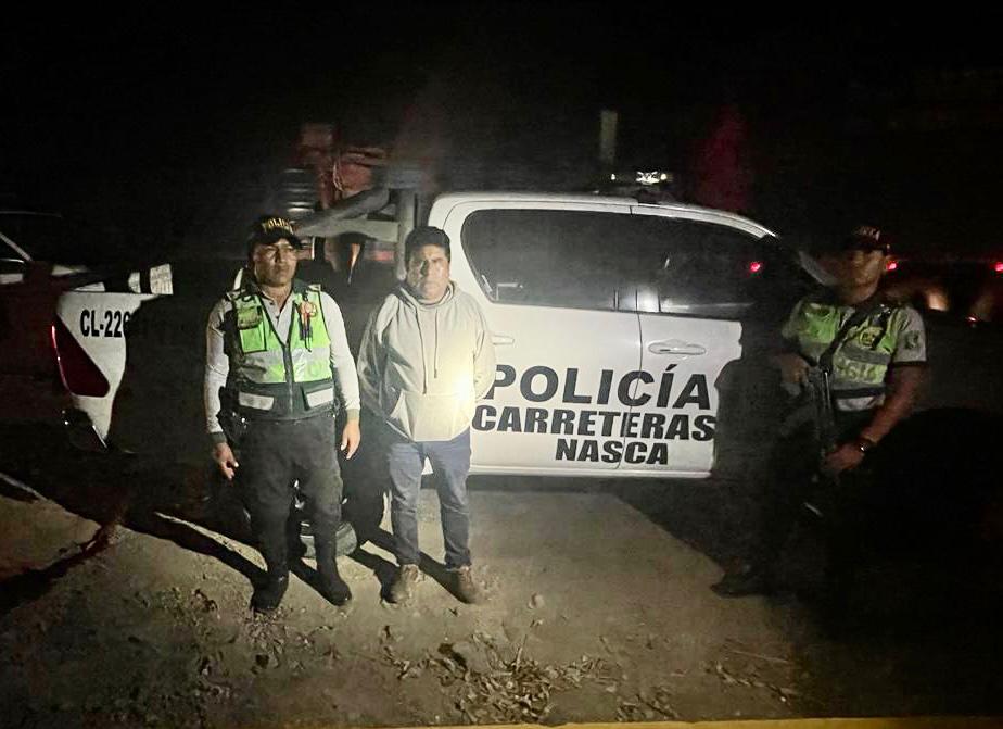 Policía con sujeto detenido en las protestas, delante de una camioneta 