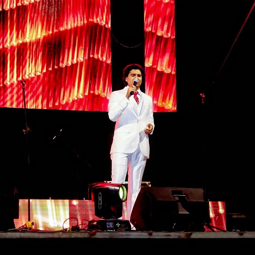 Cantando en escenario José Eduardo, José José peruano, vestido de terno blanco, canta en un escenario.