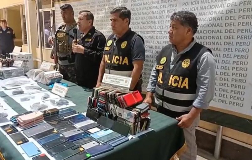 Cuatro policías frente a una mesa con pertenencias que fueron incautadas a delincuentes que las obtuvieron durante asaltos.