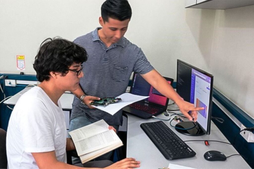 Un profesor señala con un mano la pantalla de la computara. Frente a él, un estudiante mira. Ninguna tecnología es mala por naturaleza. Es el uso lo que determina su consecuencias positivas o negativas. (Foto: Andina).