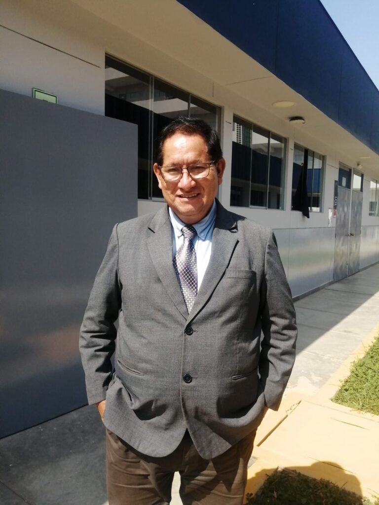 Elmer López vestido con terno y manos en los bolsillo, sonríe.