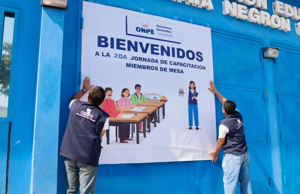 Dos trabajadores de ONPE colocan un cartel en la puerta del colegio María Negrón en Trujillo, en la víspera de las Elecciones Generales 2026 que se desarrollará este domingo 12 de abril.